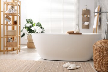 Set of different bath accessories and soap on tub in bathroom