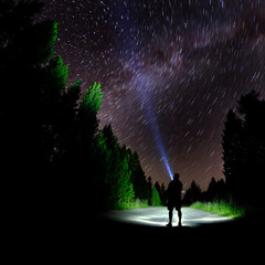 Man Standing in Dark Stars with Flashlight Forest Night Sky