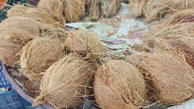 Closeup of a pile of whole coconuts with fibrous husks displayed for sale at a market