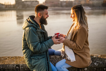 Woman giving presents to her man while they enjoy spending time together outdoor.