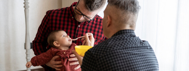 Horizontal banner or header with male gay couple with adopted baby girl at home - Two handsome dads...