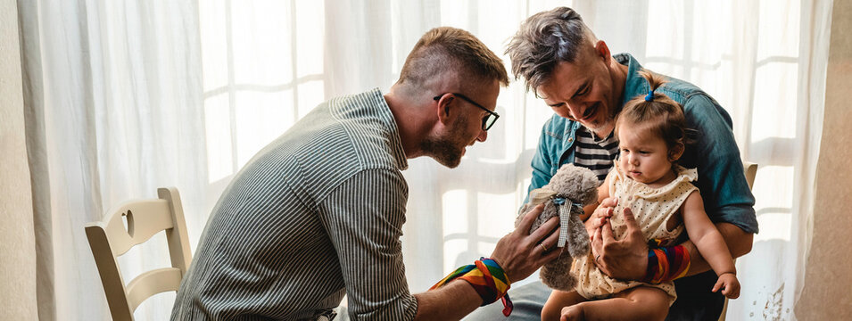 Horizontal banner or header with male gay couple with adopted baby girl at home - Two handsome fathers playing with their daughter - Lgbtq family at home - Diversity concept LGBTQ family relationship
