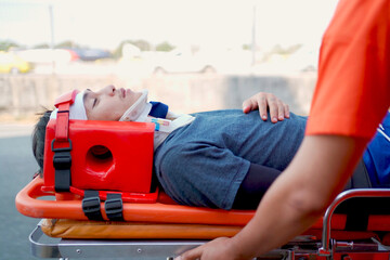 Emergency medical service team is rescuing Asian young manใ The emergency response team is trying to administer first aid to an Asian man who has had an accident on the side of the road.