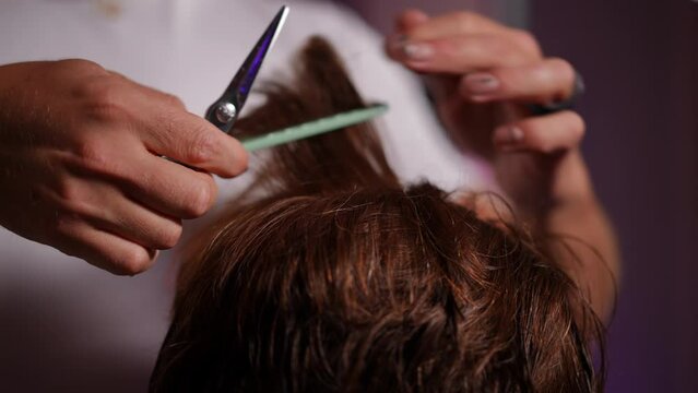 Close-up. An unrecognizable male hairdresser cuts hair with barber scissors on a wig worn on a male mannequin head