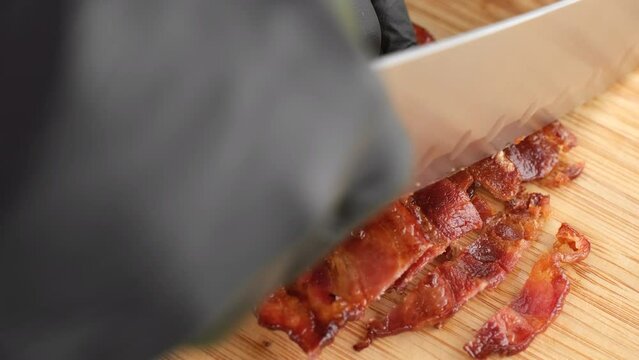 Chef chopped fried bacon on wooden board, close up