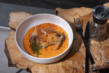 A plate with fried chicken and carrot and potato puree on wooden table