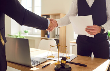 Cropped photo of a male lawyer working in office shaking hand with a man client standing at the...