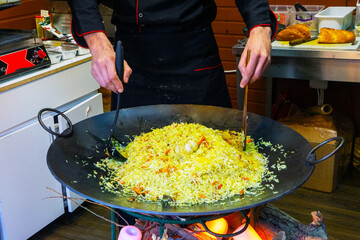 Cook prepares pilaf, a dish of rice and meat on a campfire in the kitchen of the restaurant.