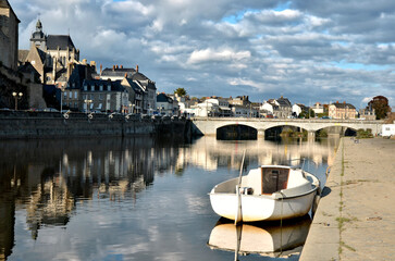 Mayenne river in the town of the same name with Notre-Dame basilica and a little boat, commune in the Mayenne department in north-western France