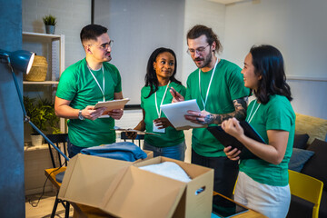 Smiling activists putting second-hand clothes in cardboard boxes for donation.