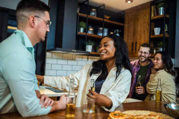 Two diverse young friends laughing together during a dinner together in a friend's kitchen