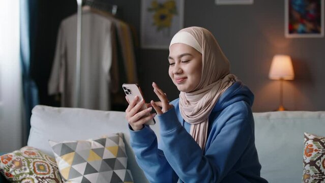 Muslim woman using phone, reacting expressively. Emotional disgruntled irritated annoyed woman puts down phone, rolling eyes. Change of mood and emotions. Woman in hijab sees bad news, angry comment.