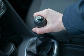 The driver's hand holds the gear lever of a passenger car in winter