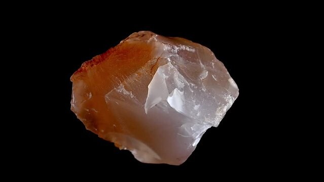 Carnelian (translucent variety of chalcedony - silicon dioxide) sample rotating slowly against a black background.	