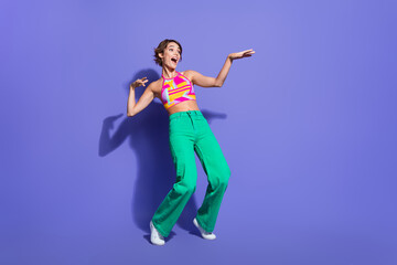 Fototapeta na wymiar Photo of cheerful adorable carefree girl dressed stylish clothes standing tiptoes looking empty space isolated on purple color background