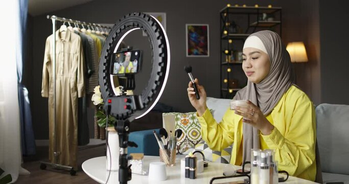 Female beauty blogger recording video. Muslim woman female blogger in hijab shoots records videos for social networks, tests cosmetics, care, decorative products for face. Aspiring Beauty Blogger.