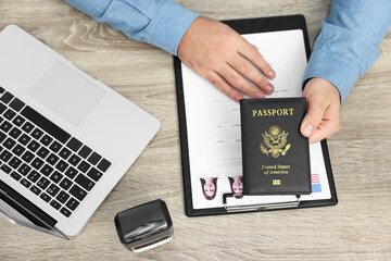 Immigration to United States of America. Man with passport and visa application form at wooden...
