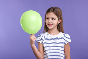 Happy girl with green balloon on violet background