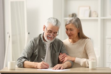Senior couple signing Last Will and Testament indoors