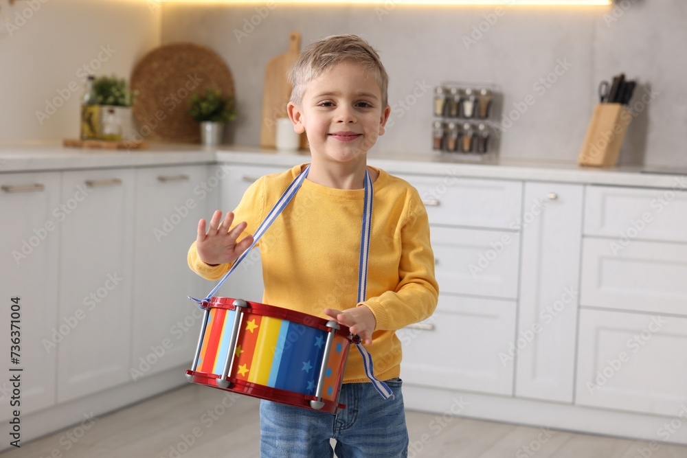 Poster Little boy playing toy drum in kitchen