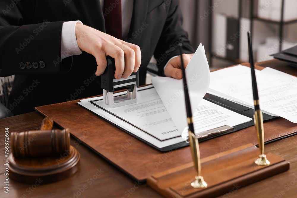 Poster Notary stamping document at wooden table in office, closeup