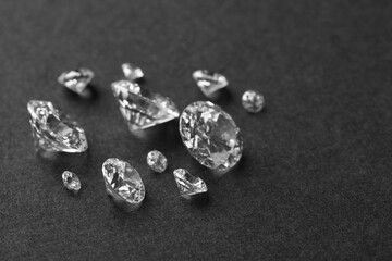 Beautiful shiny diamonds on gray table, closeup. Space for text