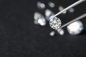 Tweezers with beautiful shiny diamond against dark blurred background, closeup. Space for text