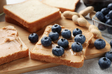 Tasty peanut butter sandwiches with fresh blueberries on table, closeup