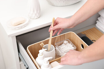 Bath accessories. Woman organizing personal care products indoors, closeup