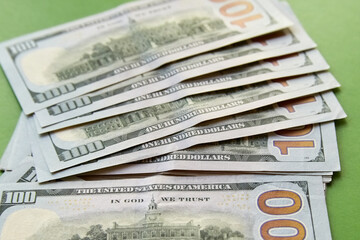 Hundred-dollar bills carelessly scattered on a green background.