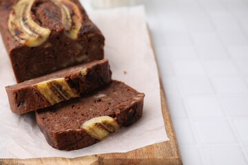 Delicious banana bread on white tiled table, closeup. Space for text