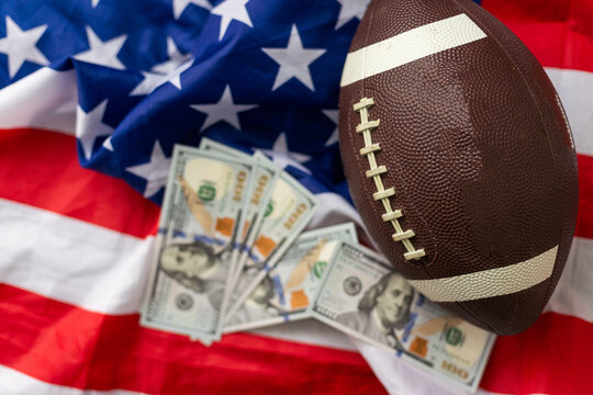 Money and rugby ball on american flag background, closeup. Concept of sports bet