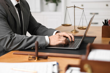 Notary working with laptop at wooden table in office, closeup