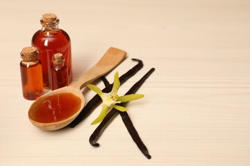 Aromatic vanilla extract, pods and flower on white wooden table. Space for text