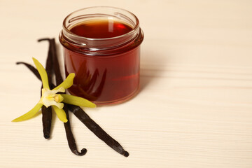 Aromatic vanilla extract, pods and flower on white wooden table. Space for text