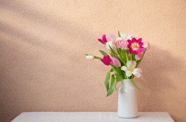 tulips in vase on table on background wall