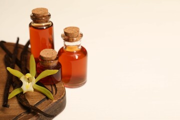 Aromatic vanilla extract, pods and flower on white table, closeup. Space for text
