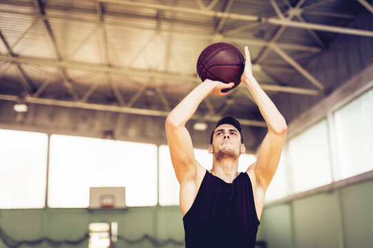 Man shooting basketball in indoor gym