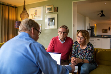 Senior couple talking to a real estate agent in living room