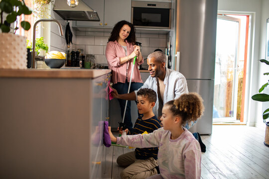 Children cleaning the kitchen with parents at home