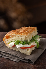 Focaccia pizza filled with mozzarella, salad and tomatoes. Side view