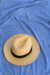 Fototapeta na wymiar Straw hat resting on a blue beach towel. No people.