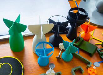 Prototype model of rocket bomb tip printed on 3D printer. Small colored models of tail fins, tail cone printed on 3D printer from molten plastic on table. New modern innovation printing technology