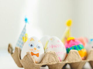 Cardboard package with decorated Easter eggs with glued and painted Easter bunny faces on a marble table