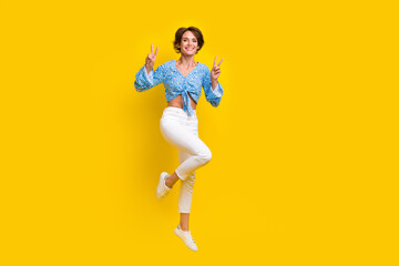 Full size photo of cheerful nice positive woman wear print blouse flying showing v-sign symbol isolated on yellow color background