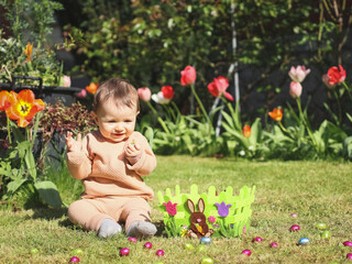 Happy baby girl with easter chocolate egg on the lawn.