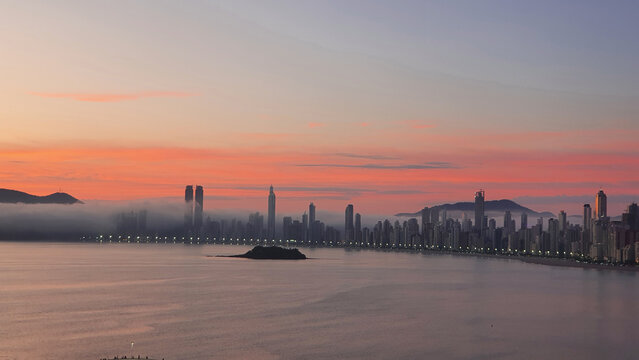 Sunrise on Balne&aacute;rio Cambori&uacute; beach, Santa Catarina, Brazil, with buildings in the blurred background.