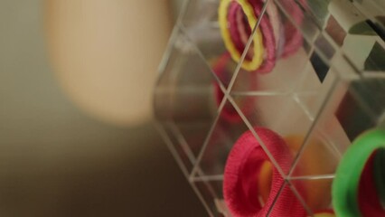 Child's hand taking hair elastics from the box that organizes them by color. Organizer with fashion hair bows, hairpins and hair elastics. Baby girl hair