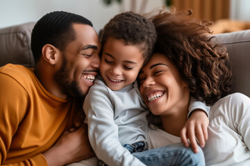 Happy african american family lying on sofa and laughing at home
