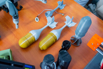 Prototype model of rocket bomb tip printed on 3D printer. Small colored models of tail fins, tail...